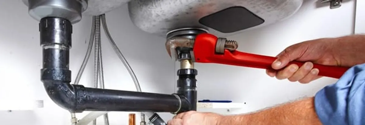 Garbage disposal repair technician tightening the sink drain and disposal connection in Little Rock, AR
