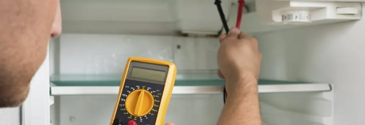 Refrigerator repair technician testing electrical components with a multimeter in Little Rock, AR