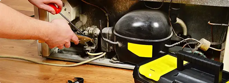 Refrigerator repair technician fixing the compressor and wiring in Little Rock, AR